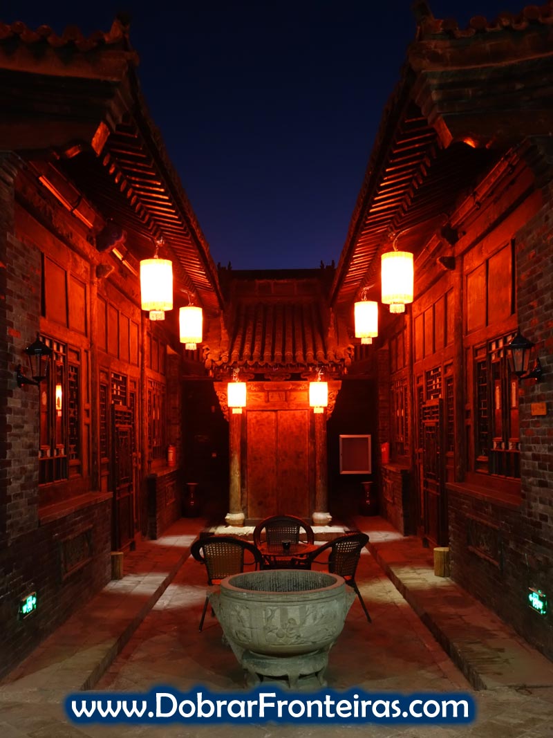 Pátio de hotel em edifício antigo chinês à noite, iluminado por lanternas vermelhas, na cidade de Pingyao, China