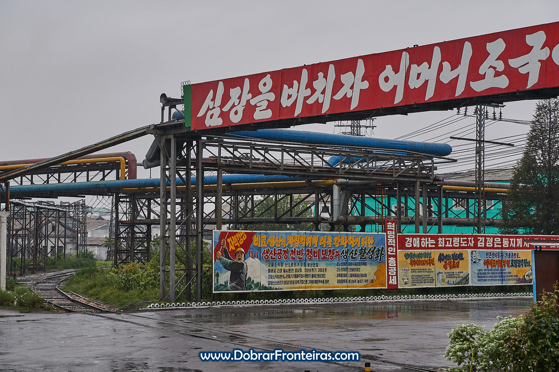 Caminho de ferro, tubagens e cartazes em industria de fertilizantes na Coreia do Norte
