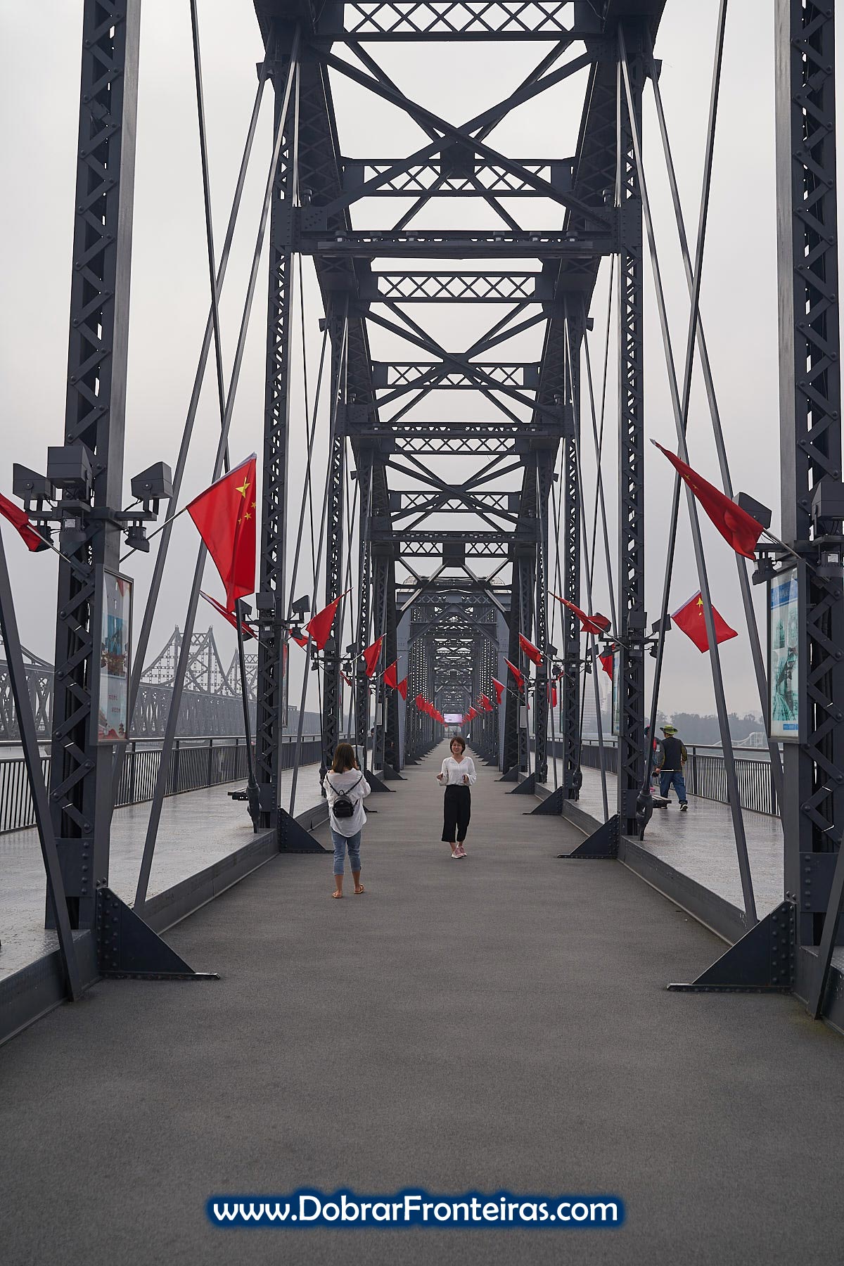 Mulheres a tirar fotografia na ponte sobre o rio Yalo na fronteira da China com a Coreia do Norte