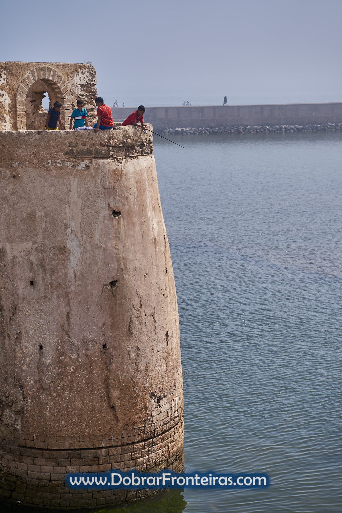 Rapazes a pescar em muralha em Mazagão, Marrocos